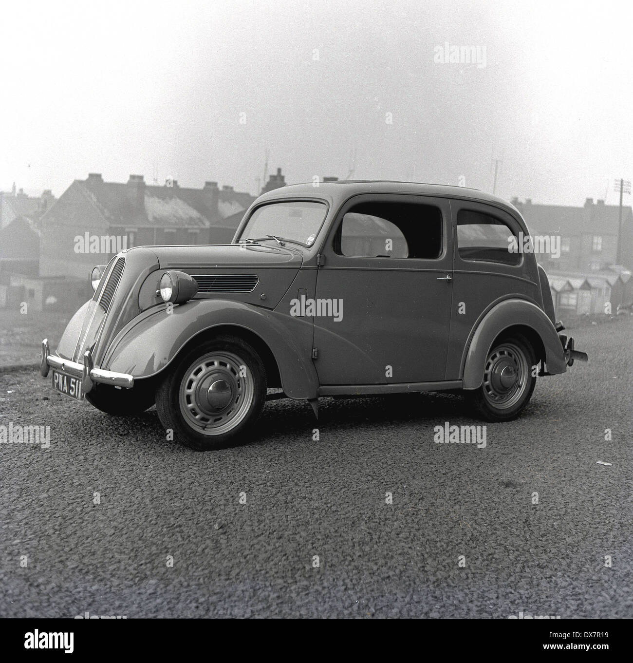 1950s. Foto storiche di un post WW11 auto, una Morris 10, parcheggiata con la città industriale di Sheffield, in Inghilterra in background. Foto Stock