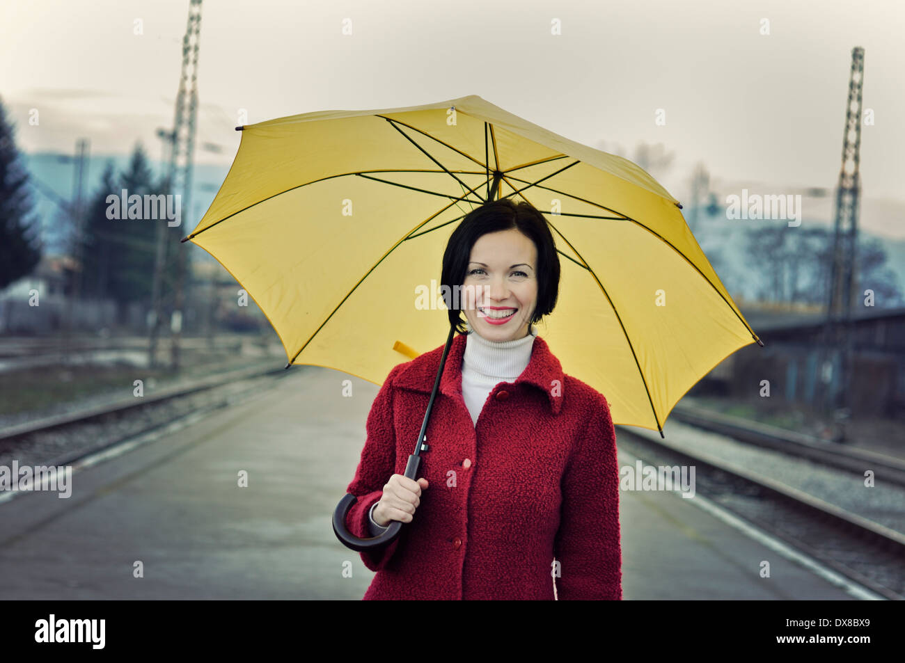 Sorridente metà donna adulta holding Ombrello giallo Foto Stock