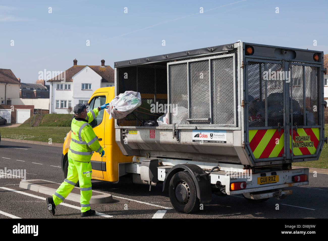 Consiglio lavoratore in alta visibilità abbigliamento di gettare i rifiuti in piccole raccolta rifiuti carrello. Foto Stock