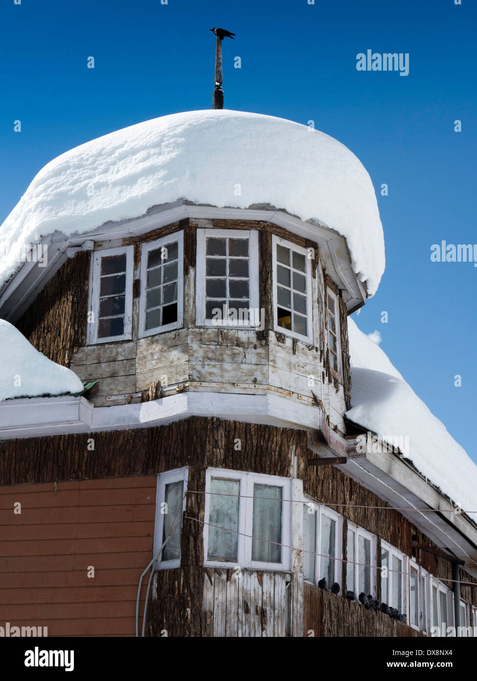 India, Kashmir Gulmarg, Himalayan Ski Resort, neve laden il tetto del piccolo hotel locale Foto Stock