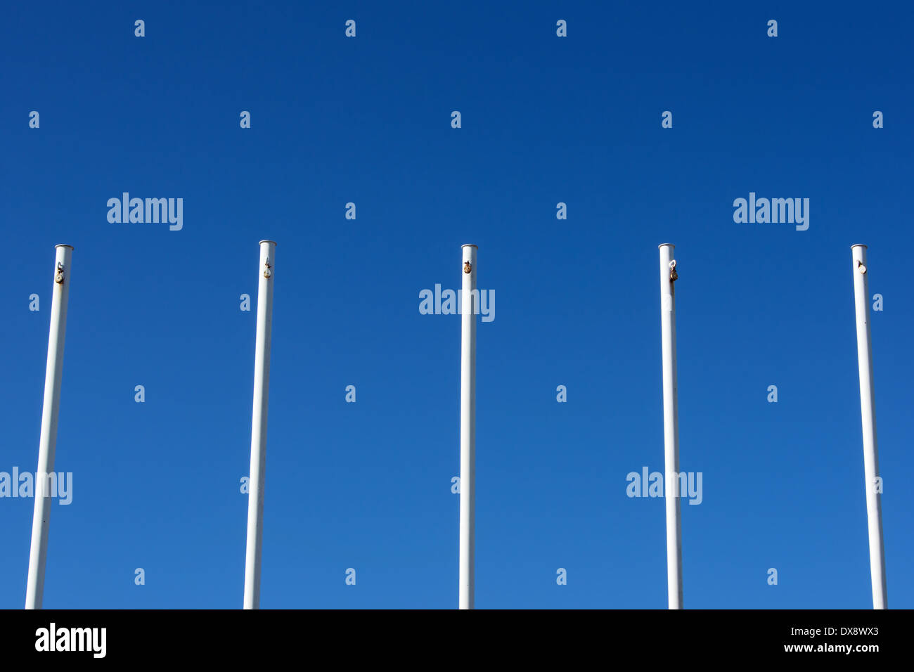 Vuoto bandiera bianca poli contro il cielo blu Foto Stock
