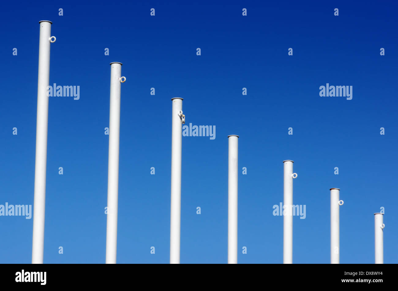 Vuoto bandiera bianca poli contro il cielo blu Foto Stock