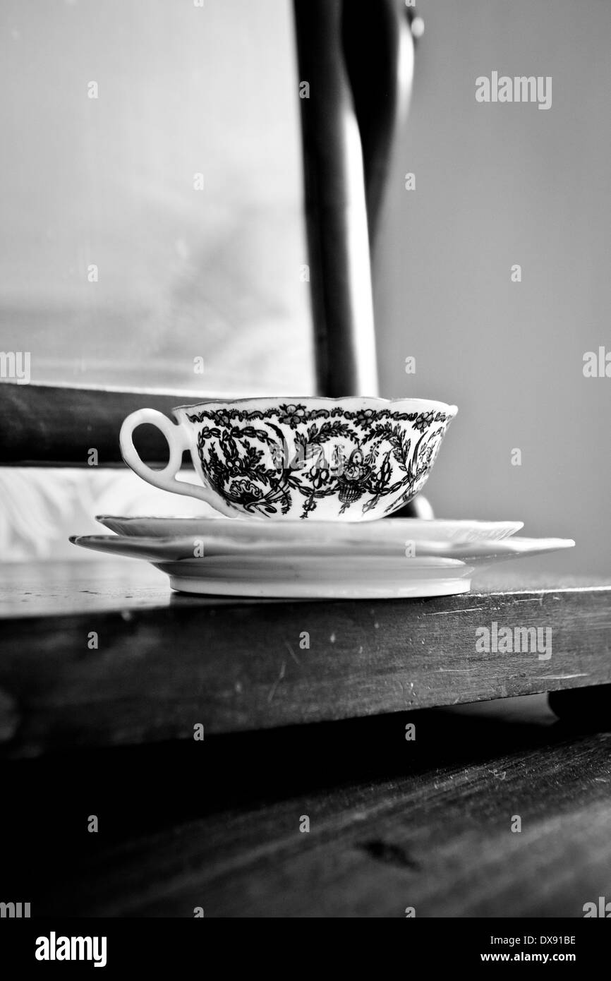 In bianco e nero la Cina tazza e piattino in legno tavolo vestito. Foto Stock