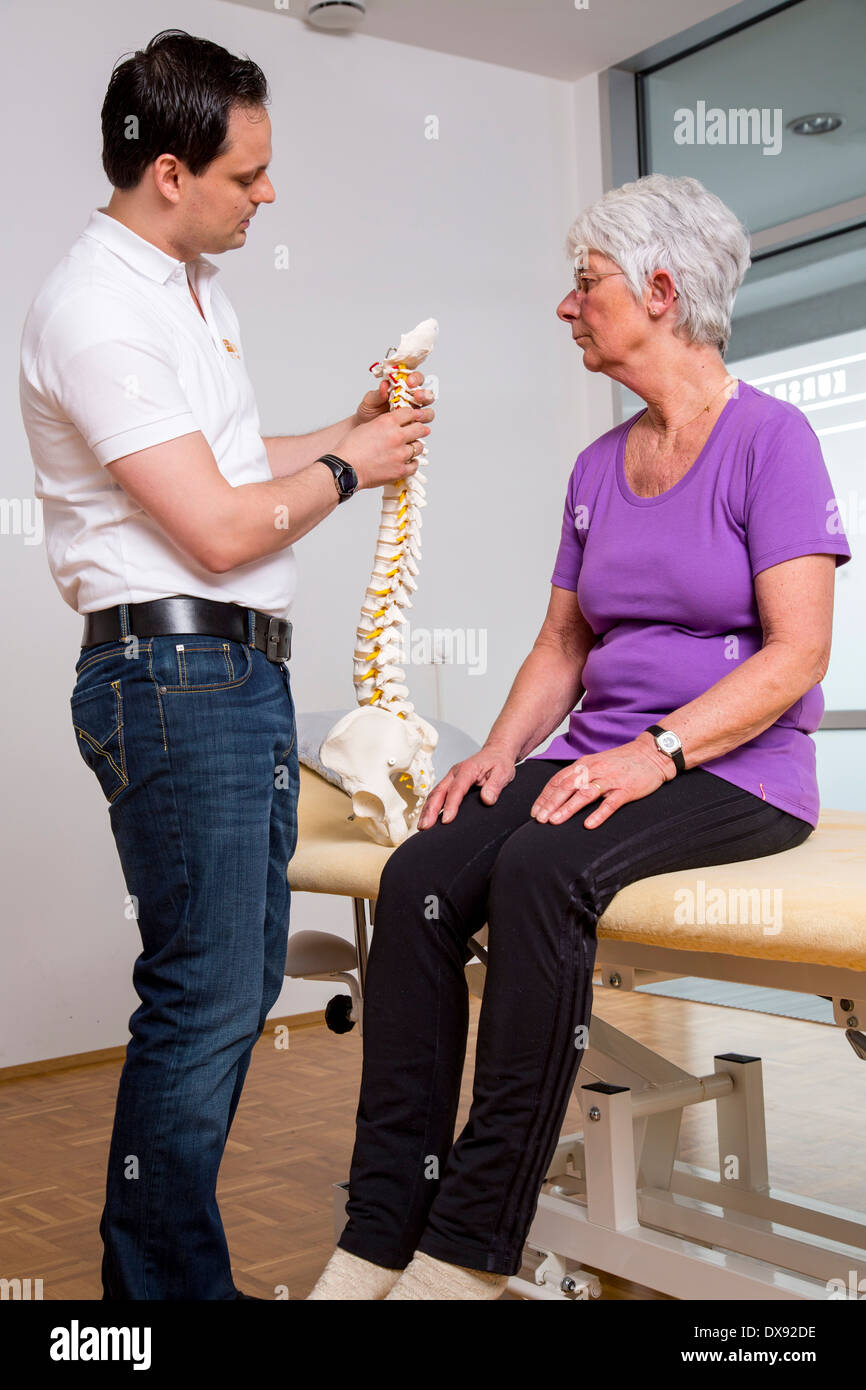 La pratica di fisioterapia terapista con paziente spiegazione del problema le aree e gli approcci di terapia, la spina dorsale del modello. Foto Stock