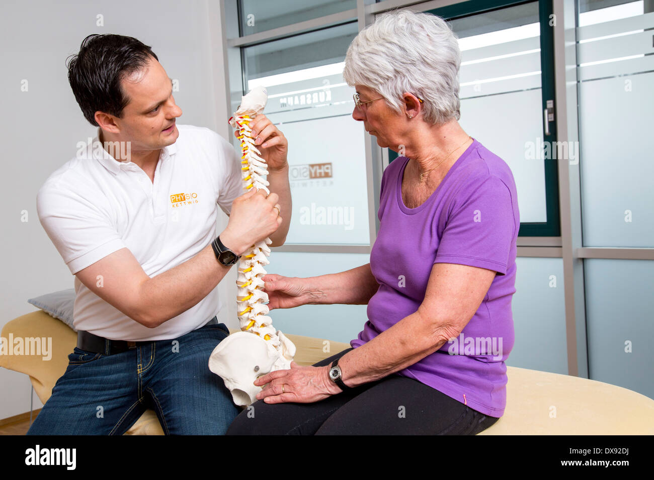 La pratica di fisioterapia terapista con paziente spiegazione del problema le aree e gli approcci di terapia, la spina dorsale del modello. Foto Stock