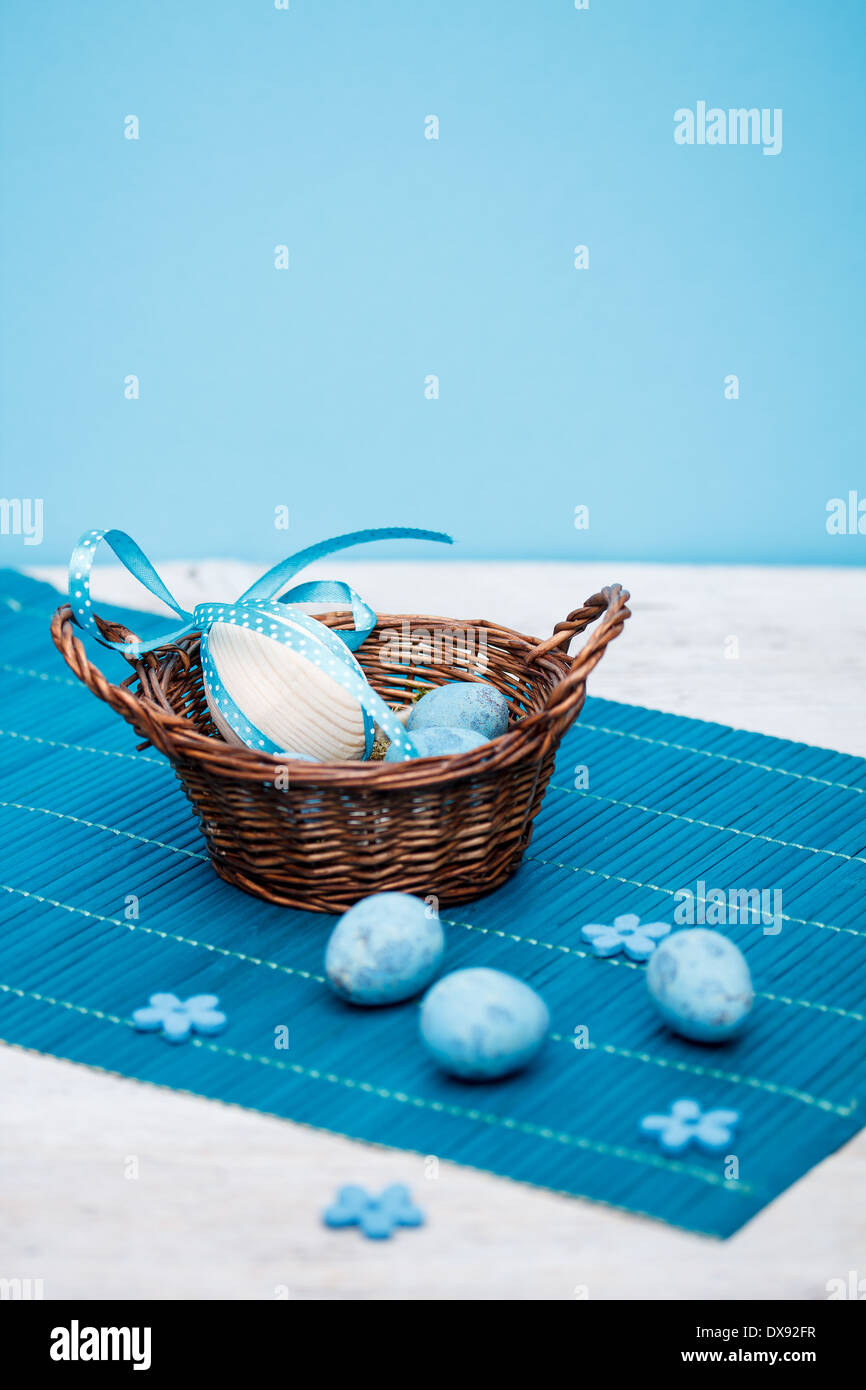 Cesto di pasqua con le uova di pasqua, sfondo blu Foto Stock