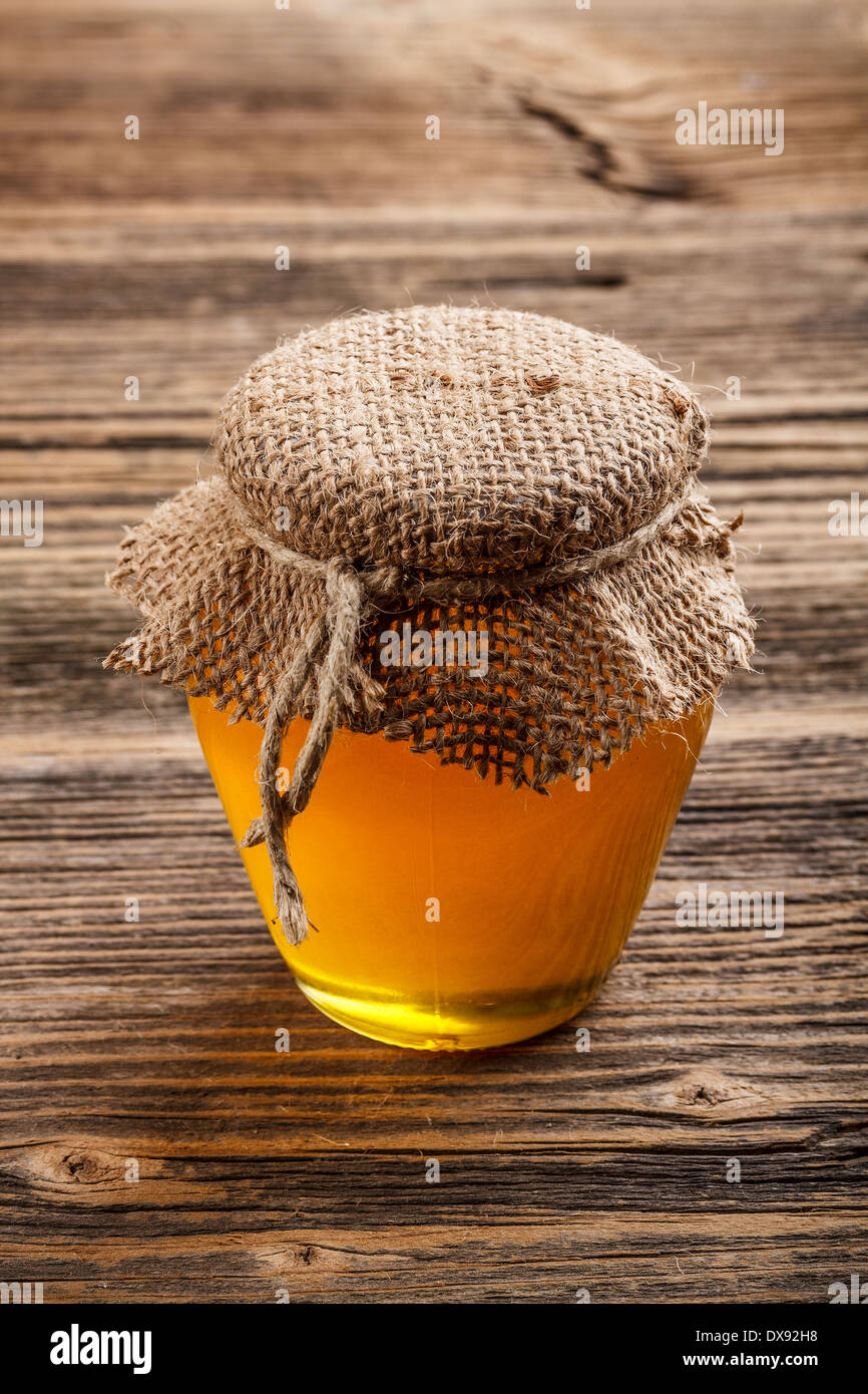 Vaso di vetro pieno di miele sul rustico sfondo di legno Foto Stock