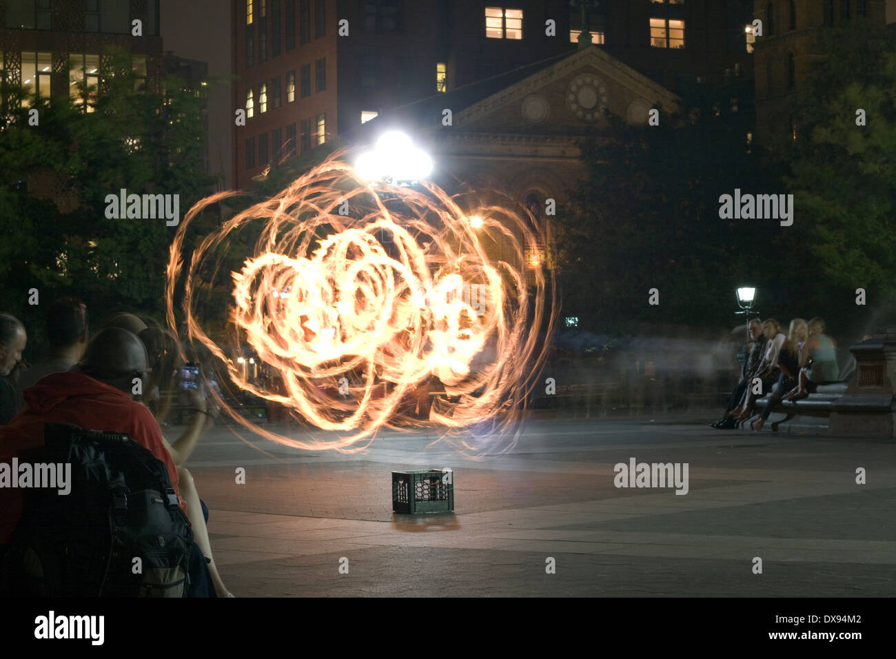 Un esecutore di strada in NYC danze per gli spettatori con una fiammante hula hoop in Washington Square Park in una notte d'estate Foto Stock