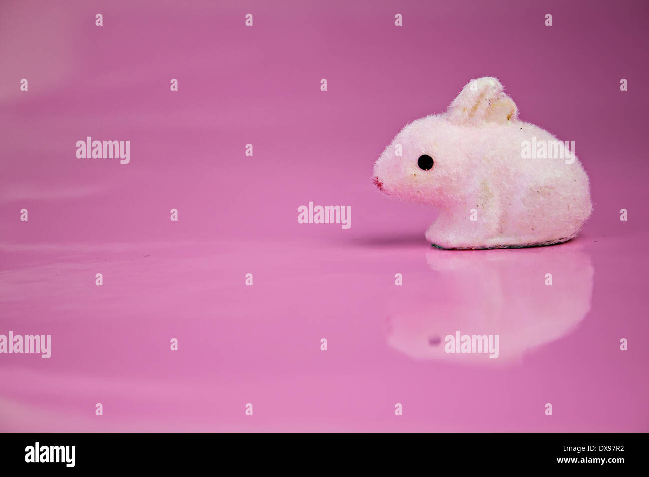 Un semplice coniglietto simpatico giocattolo su una lucida sfondo rosa. Il design di Pasqua, la molla color design Foto Stock