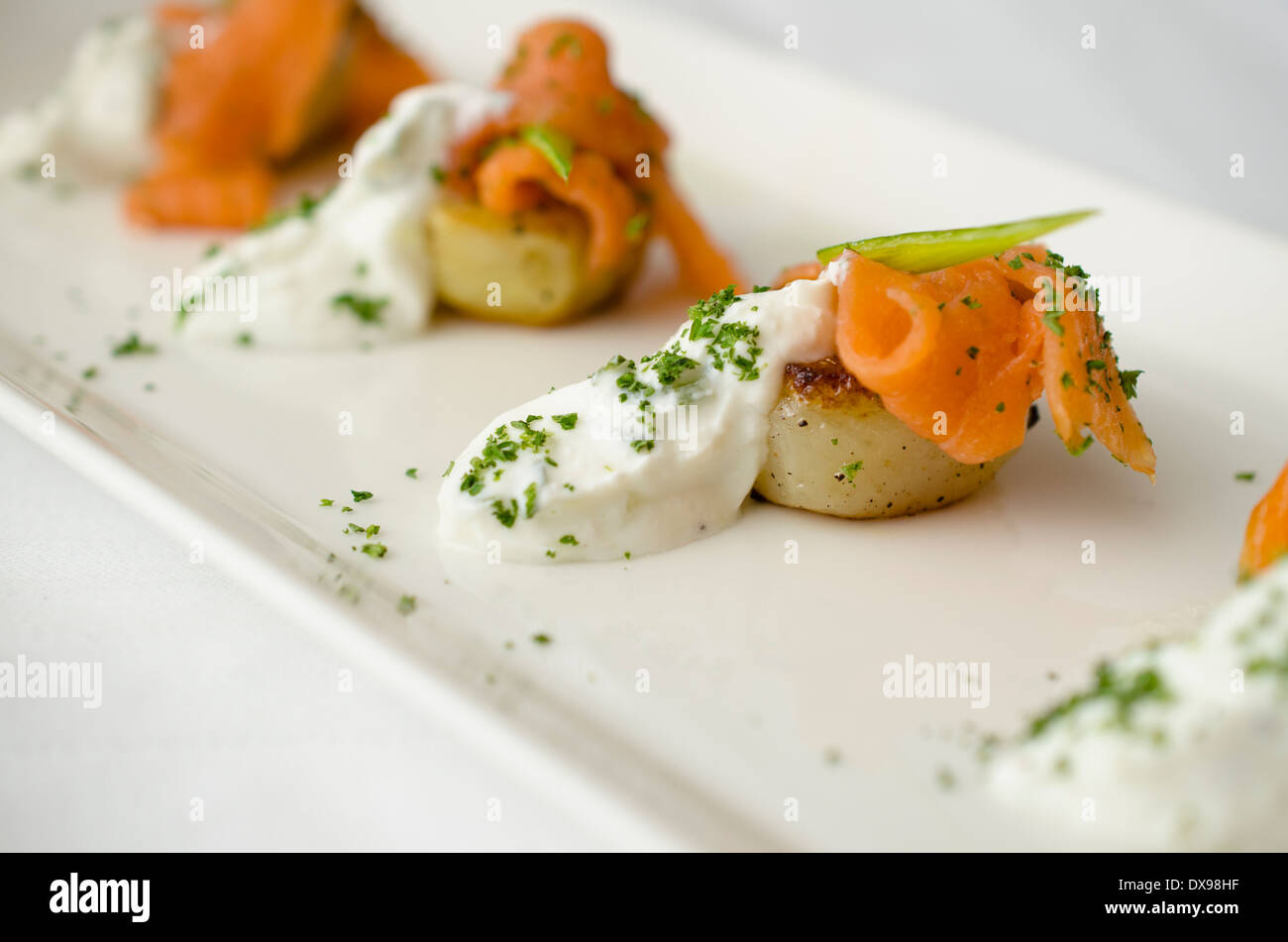 Salmone affumicato su patate fritte con yogurt alle erbe e il prezzemolo finemente tritato. Foto Stock