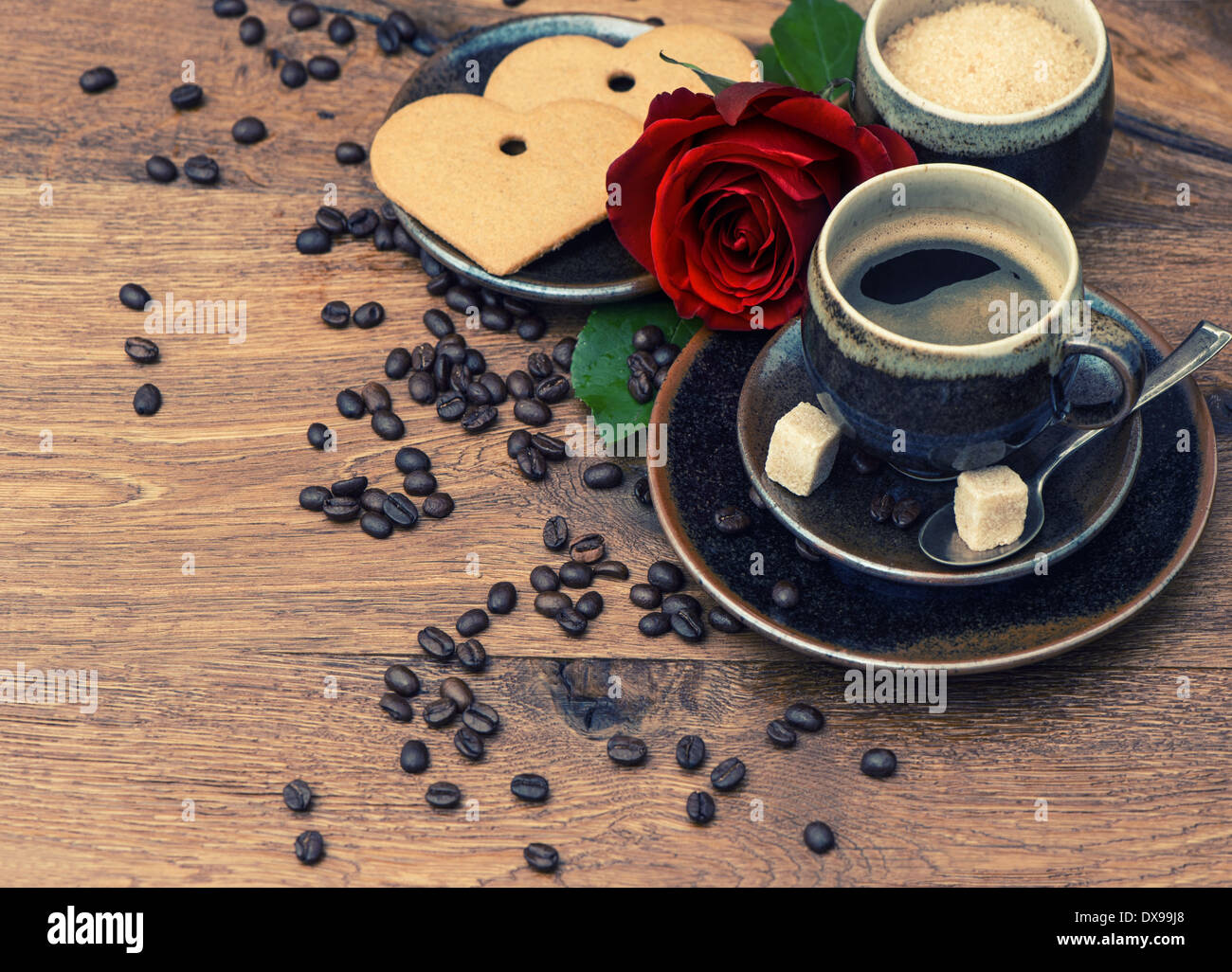 Tazza di caffè nero con Red Rose fiore e cuore la torta su sfondo di legno. Disposizione di festa Foto Stock