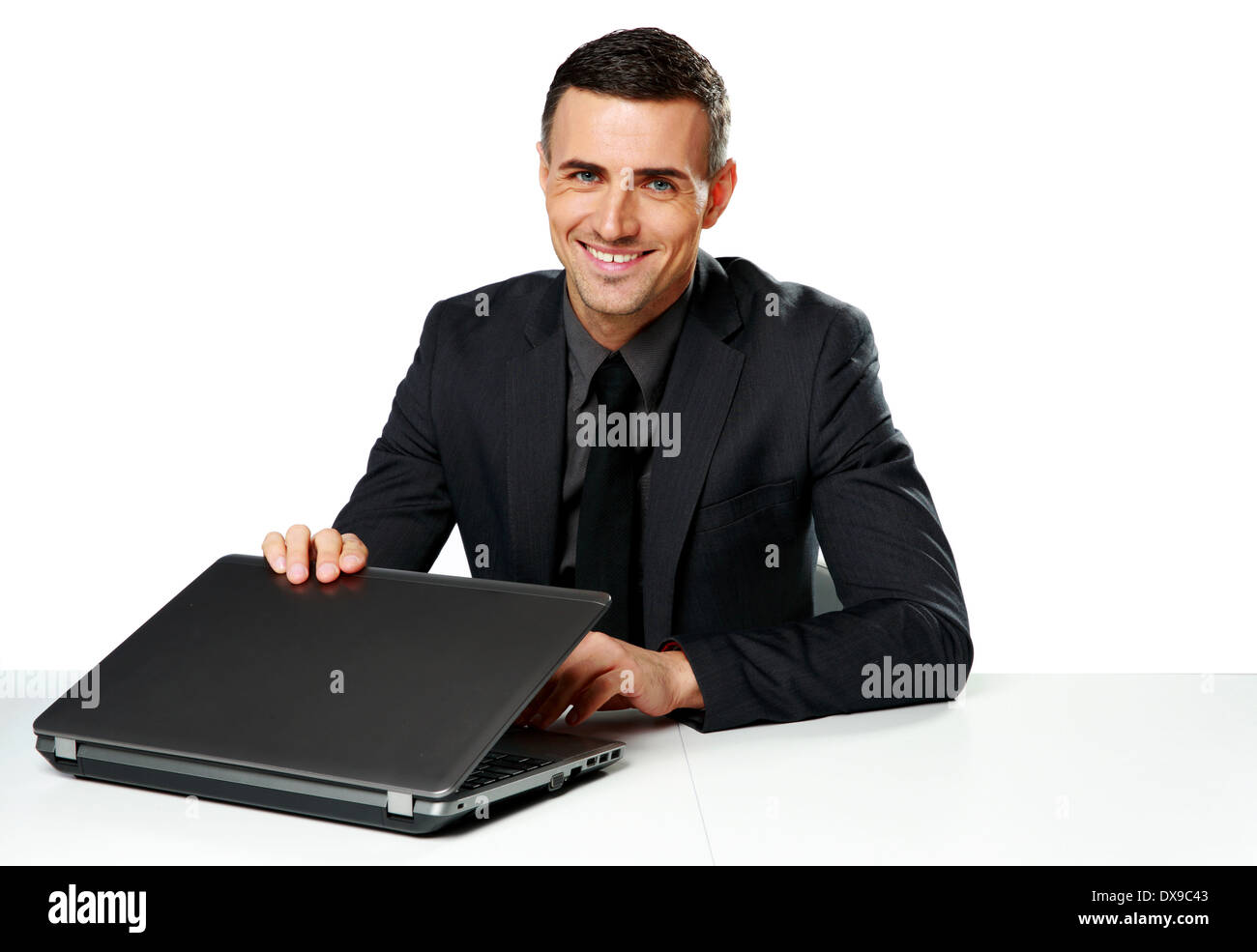 Happy businessman di sedere a tavola con il computer portatile isolato su sfondo bianco Foto Stock