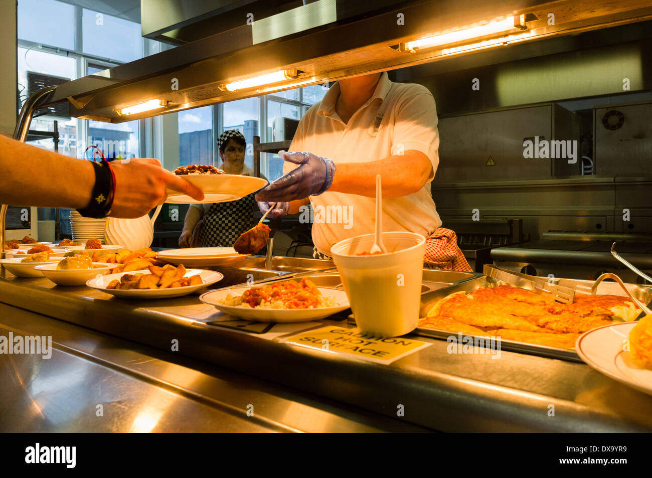 Una donna che serve da mangiare in una mensa scolastica, Wales UK Foto Stock