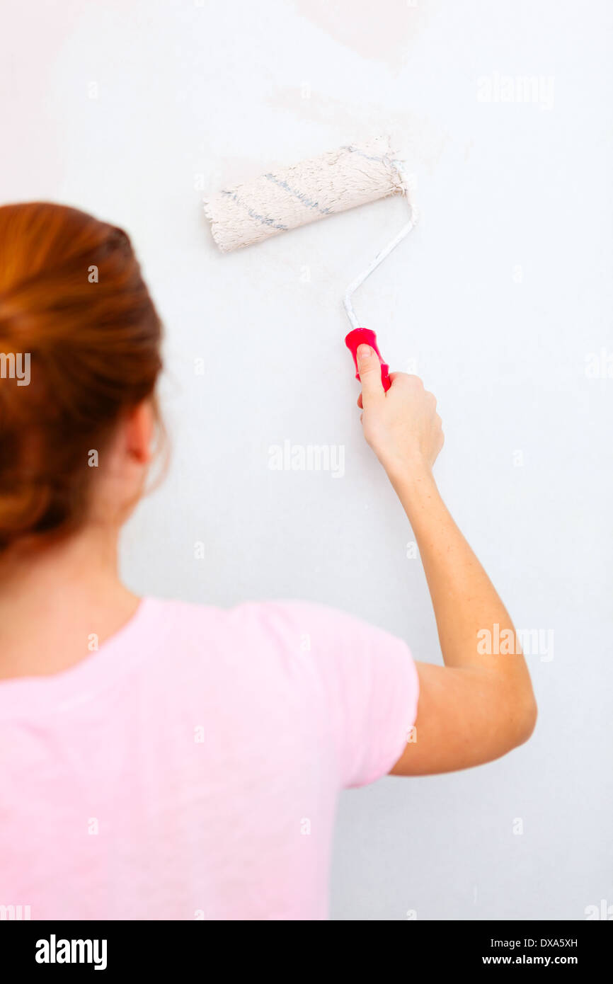 Giovane donna pittura parete con la spazzola a rullo. Foto Stock