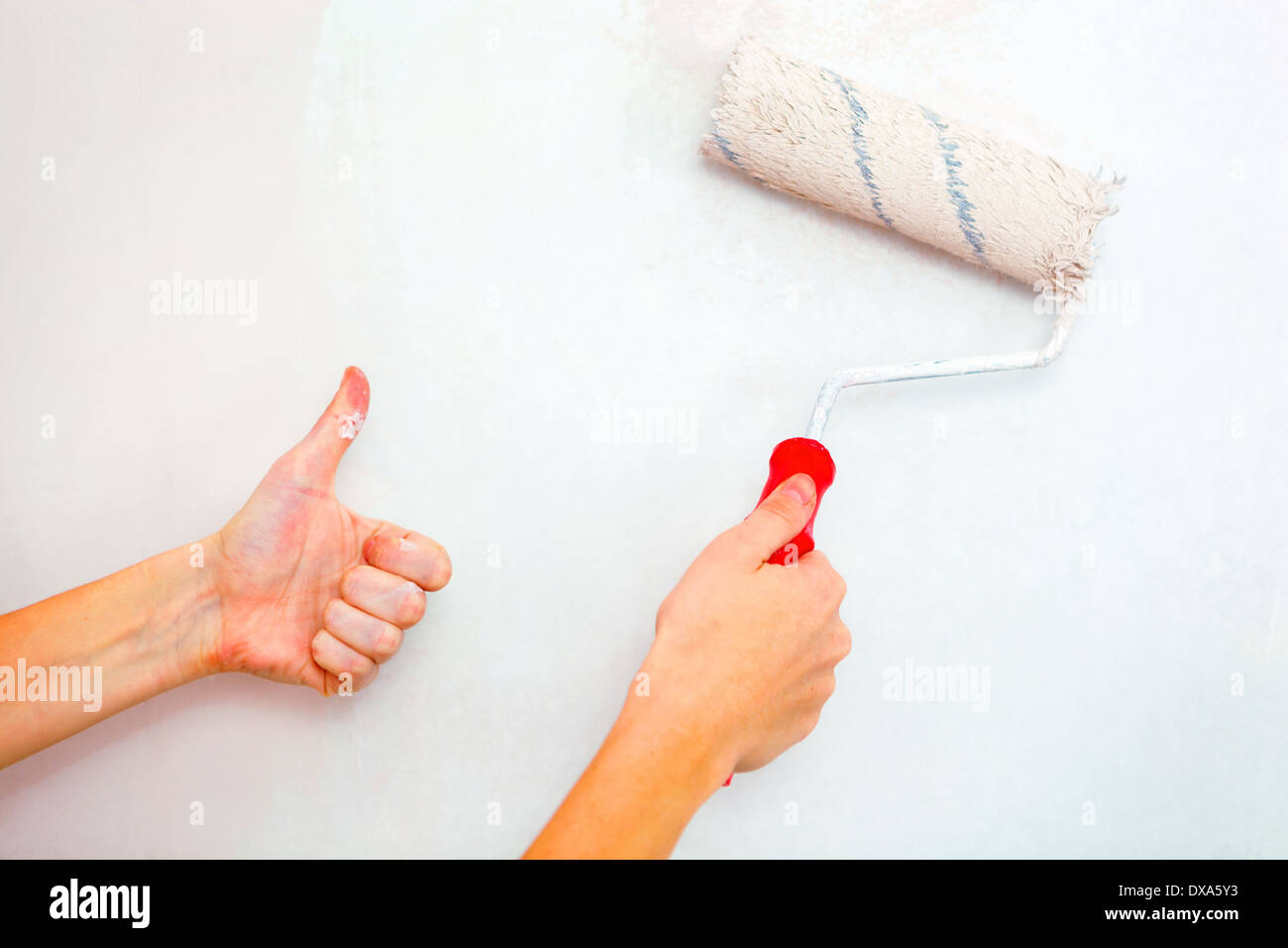 Mano con spazzola a rullo e la mano che mostra Thumbs up. Foto Stock