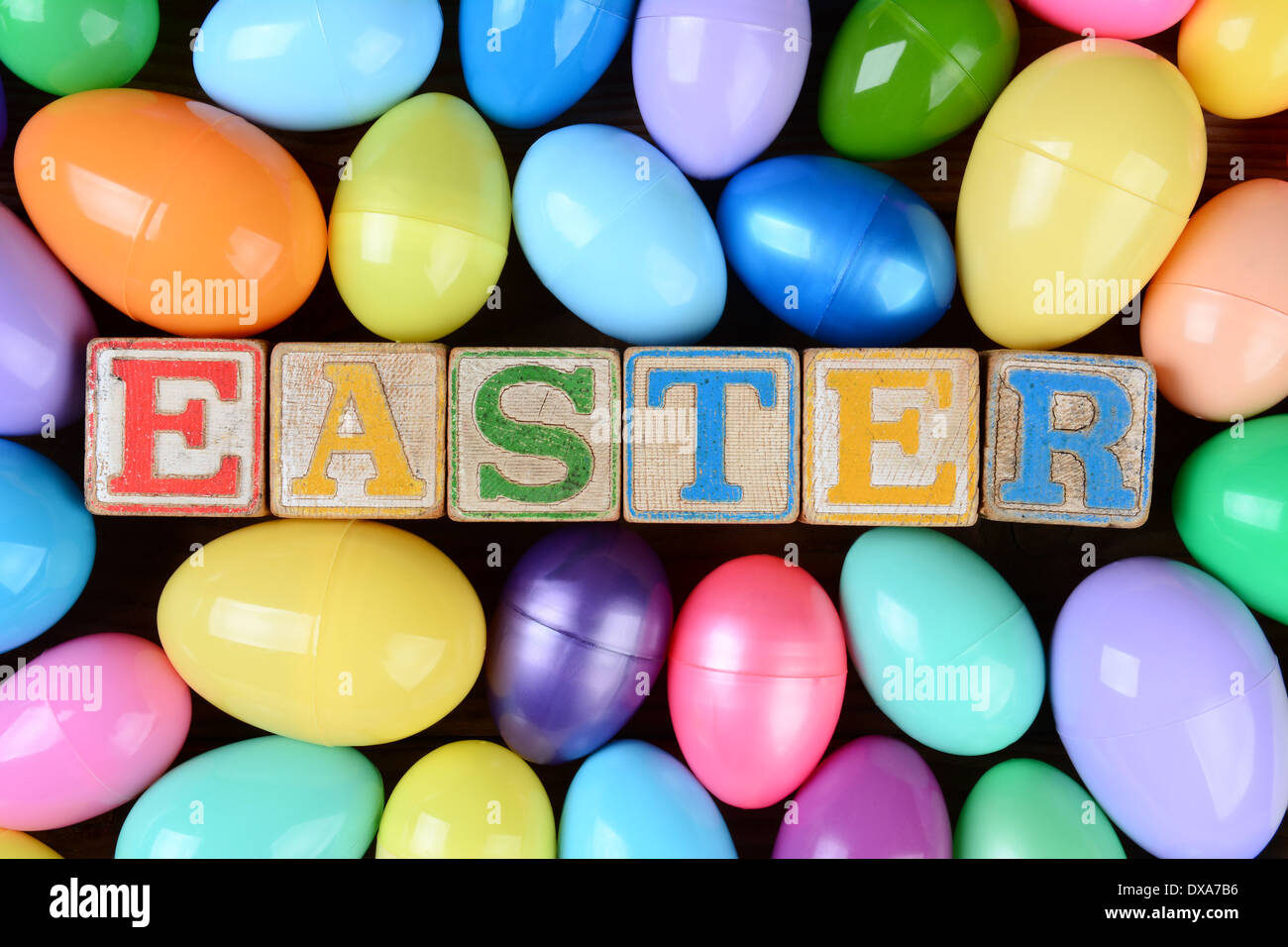 La parola Pasqua enunciato nel giocattolo per bambini blocchi circondato da un gruppo di plastica colorati uova. Foto Stock