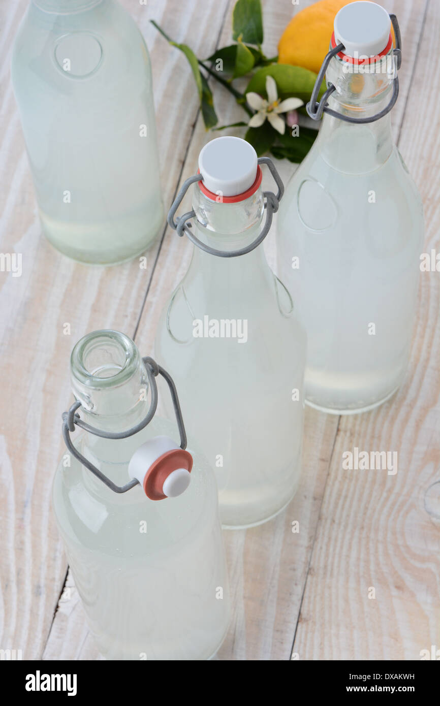 In vecchio stile frizzante bottiglie di limonata sparato da un angolo di alta. Formato verticale su un legno rustico stile rustico tavolo. Foto Stock