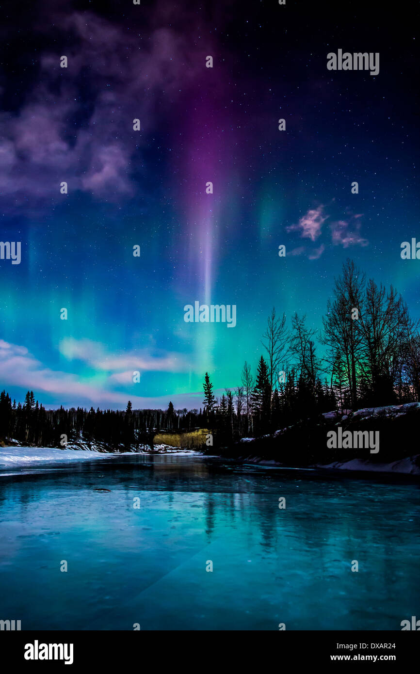 Una fiamma viola sorge fuori le luci del nord sopra il gomito River in Alberta, Canada. Foto Stock