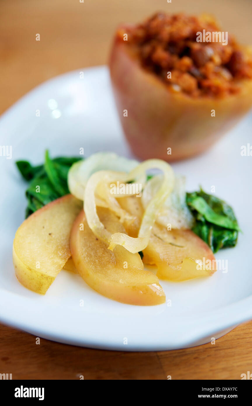 Saltata di spinaci con mele e cipolle servito con un riempito mela cotta. Foto Stock