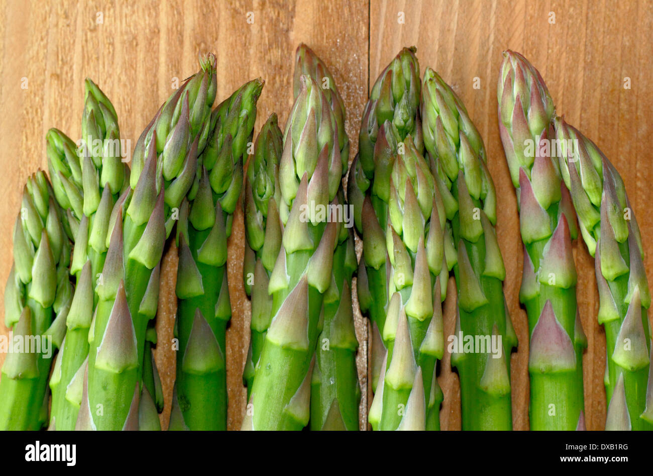 Freschi di punte di asparagi verdi/piccioli contro lo sfondo di legno, REGNO UNITO Foto Stock