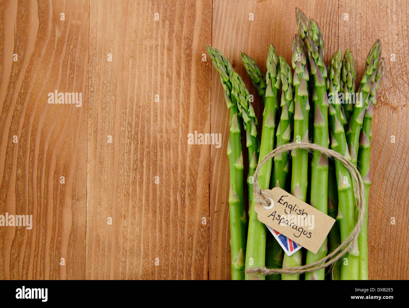 Un grappolo spargolo freschi Asparagi verdi peduncoli con etichetta contro rustico, vintage Sfondo legno, Regno Unito - con copia spazio. Foto Stock