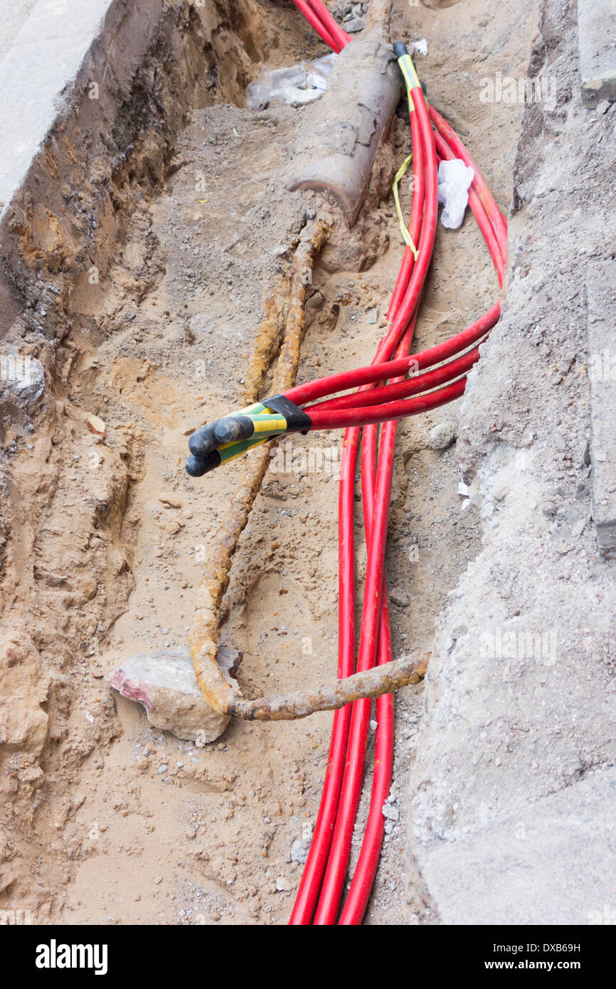 Nuova sostituzione potenza elettrica cavi prevista in una trincea con estremità sigillata per la protezione mentre in attesa di giunzione Foto Stock