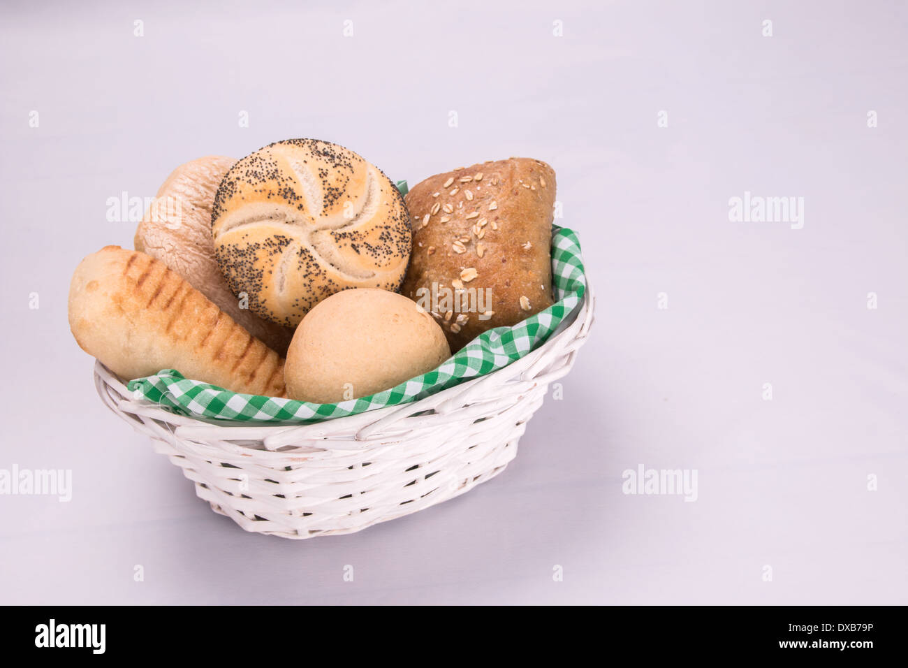 Selezione di pane, torte/panini in un cesto bianco rivestito con una verde e bianco controllo igienico su uno sfondo bianco co (3 di 5) Foto Stock