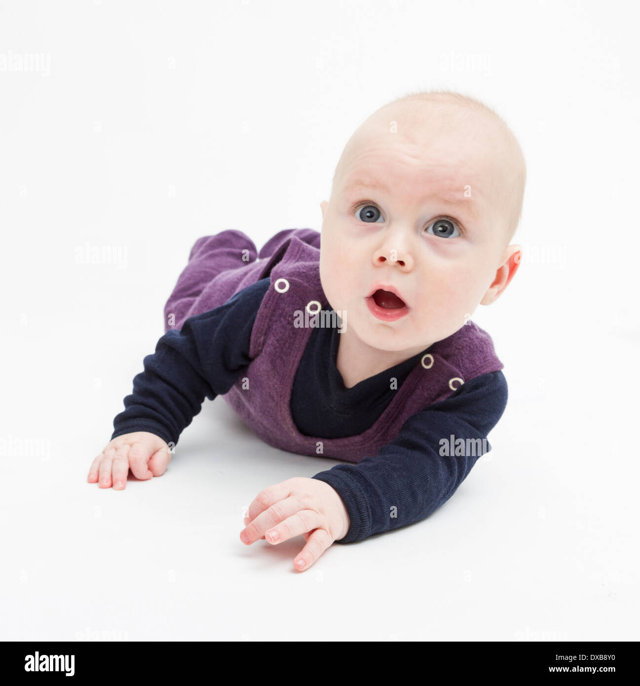 Stupito il bambino sdraiato sul pavimento. studio shot su sfondo grigio Foto Stock