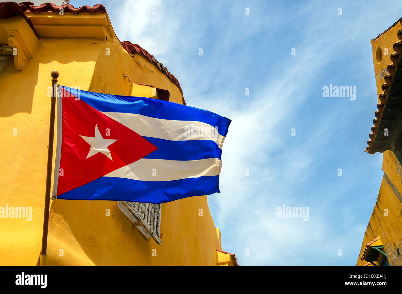 Bandiera cubana insieme contro il cielo blu e giallo edifici coloniali Foto Stock