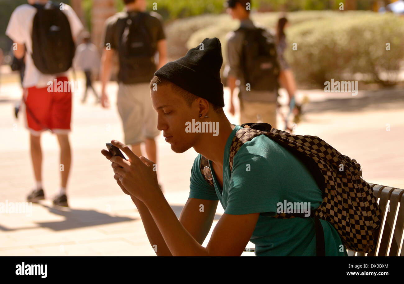 Un giovane uomo su un sms su un campus universitario. Foto Stock