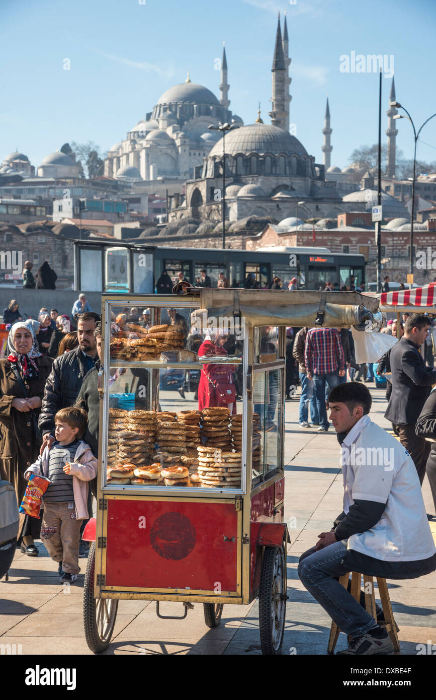 Pane Simit venditore sulla banchina a Eminonu dal Ponte di Galata, con il Solimano & Yeni moschee in backround. Istanbul, Turchia. Foto Stock