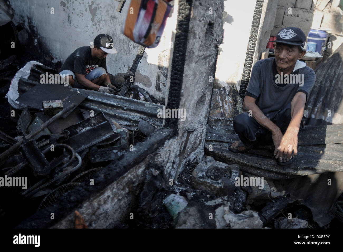 Caloocan, Filippine. 23 Mar, 2014. I residenti di vagliare le macerie di bruciato shanties dopo un incendio senza visceri una zona residenziale in Caloocan city, a nord di Manila, Filippine, 23 marzo 2014. Almeno 1700 famiglie sono rimaste senza tetto dopo 3 distinti incendi eviscerato 700 case in un arco di 24 ore. Gli incendi hanno avuto luogo come il paese osserva la prevenzione degli incendi mese.Foto: Ezra Acayan/NurPhoto Credito: Ezra Acayan/NurPhoto/ZUMAPRESS.com/Alamy Live News Foto Stock