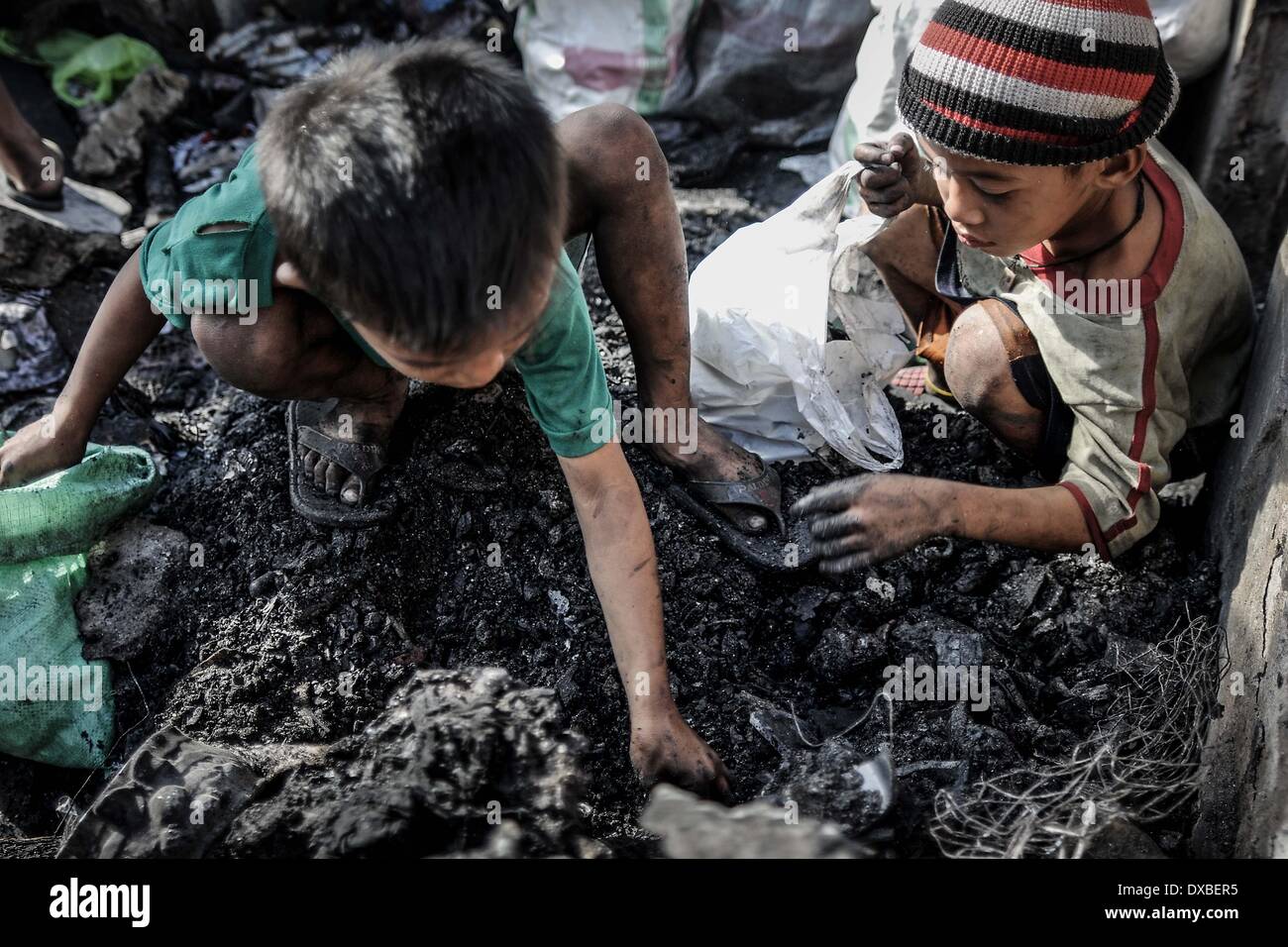 Caloocan, Filippine. 23 Mar, 2014. I bambini di vagliare le macerie per rottami di metallo dopo un incendio senza visceri una zona residenziale in Caloocan city, a nord di Manila, Filippine, 23 marzo 2014. Almeno 1700 famiglie sono rimaste senza tetto dopo 3 distinti incendi eviscerato 700 case in un arco di 24 ore. Gli incendi hanno avuto luogo come il paese osserva la prevenzione degli incendi mese.Foto: Ezra Acayan/NurPhoto Credito: Ezra Acayan/NurPhoto/ZUMAPRESS.com/Alamy Live News Foto Stock