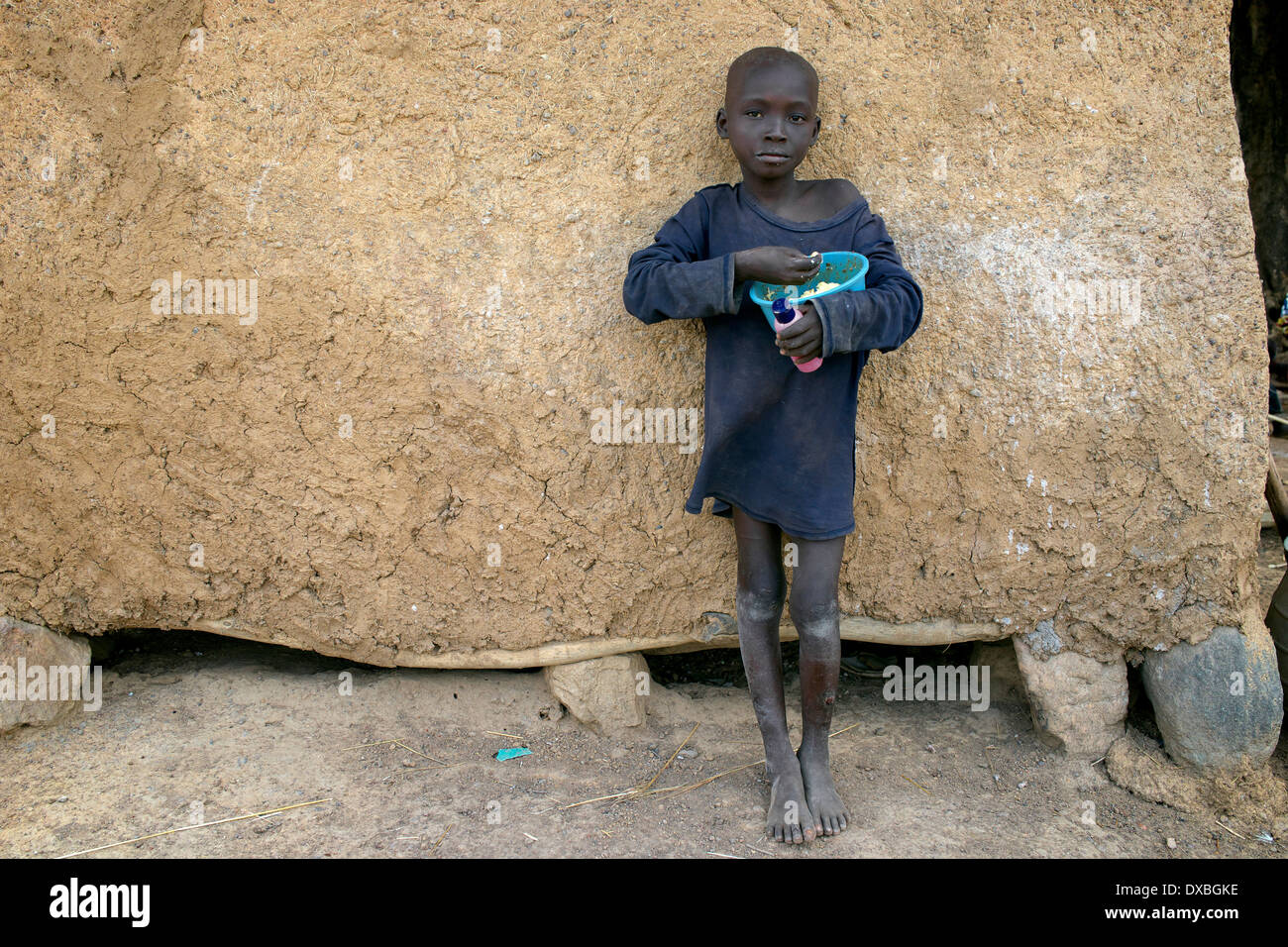 Giovane ragazzo africano di mangiare da una ciotola di plastica Foto Stock