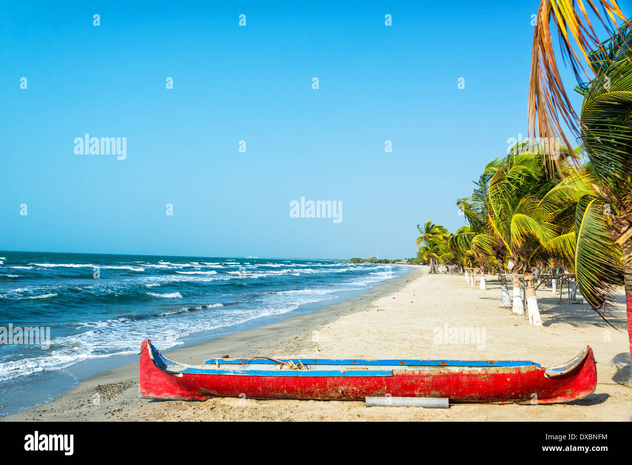 La sabbia bianca della spiaggia caraibica con una canoa rossa in primo piano Foto Stock