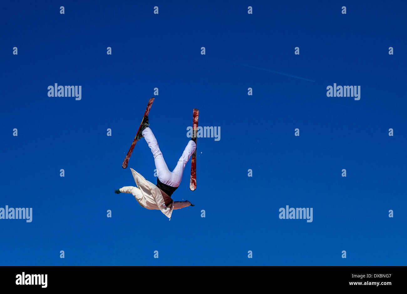 Persone: sciatore a testa in giù e fuori controllo contro un cielo blu Foto Stock