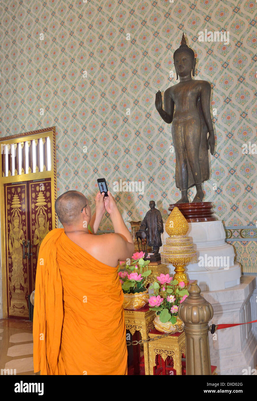 Il monaco visitante cattura una statua del buddha sul suo iPhone dalle pareti al tempio del Buddha d'oro, Wat Traimit, Bangkok, Thailandia Foto Stock