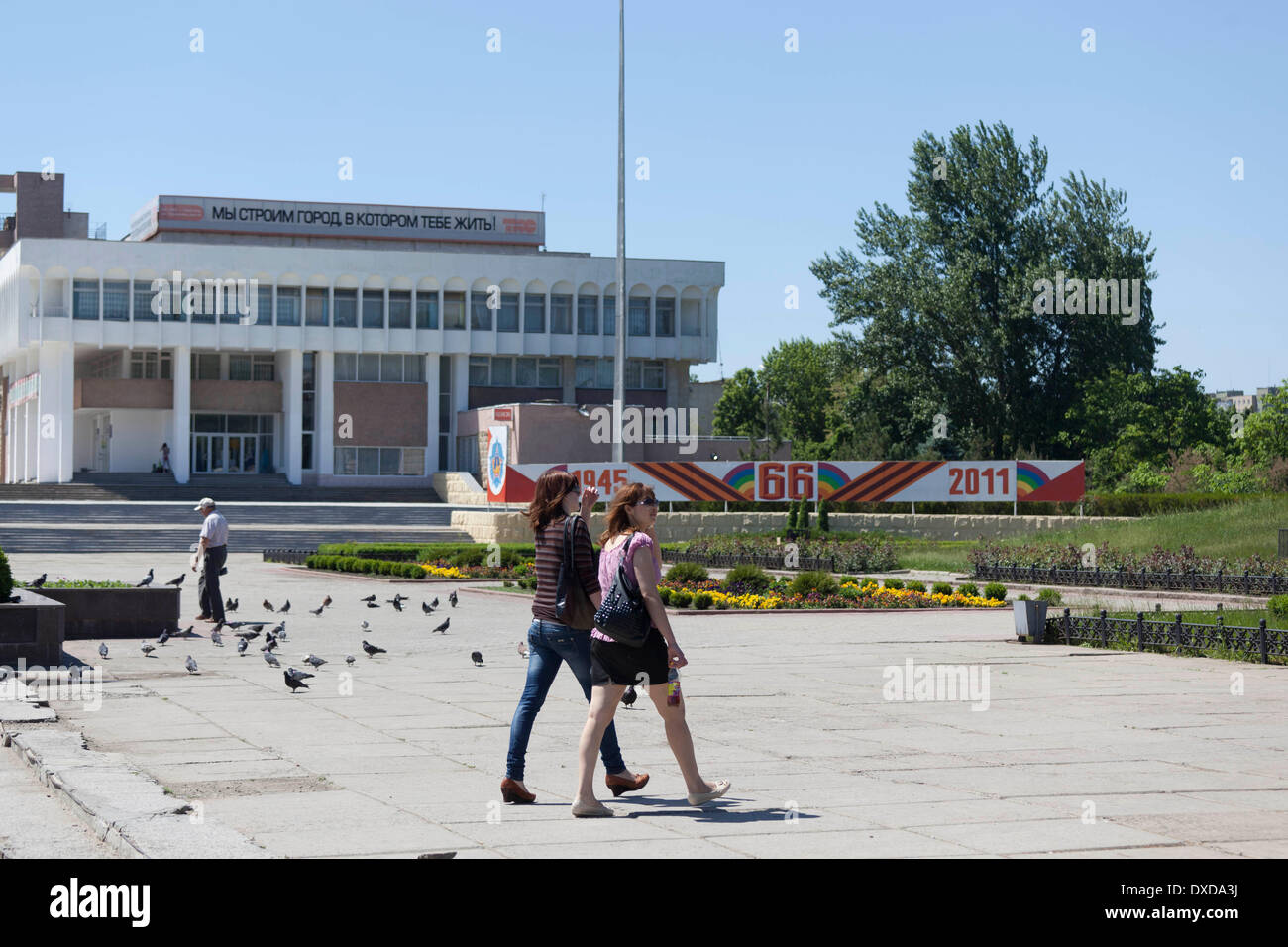 Zwei junge Frauen gehen vor Propagandainschrift, etwa "Wir errichten eine lebenswerte Stadt' und der Erinnerung an den Sieg im 2. Weltkrieg vor 66 Jahren / Propaganda iscritto: sth. come stiamo costruendo una vivace citta' / foto: Robert B. Fishman, ecomedia,, 26.05.2011 Foto Stock