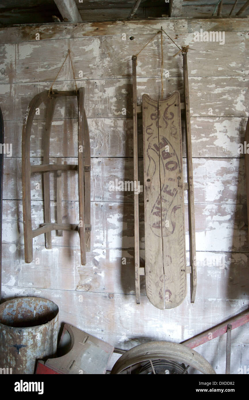 A tutta lunghezza vista di sled antichi appesi in una stalla a Curran Homestead, Orrington, Maine. Foto Stock