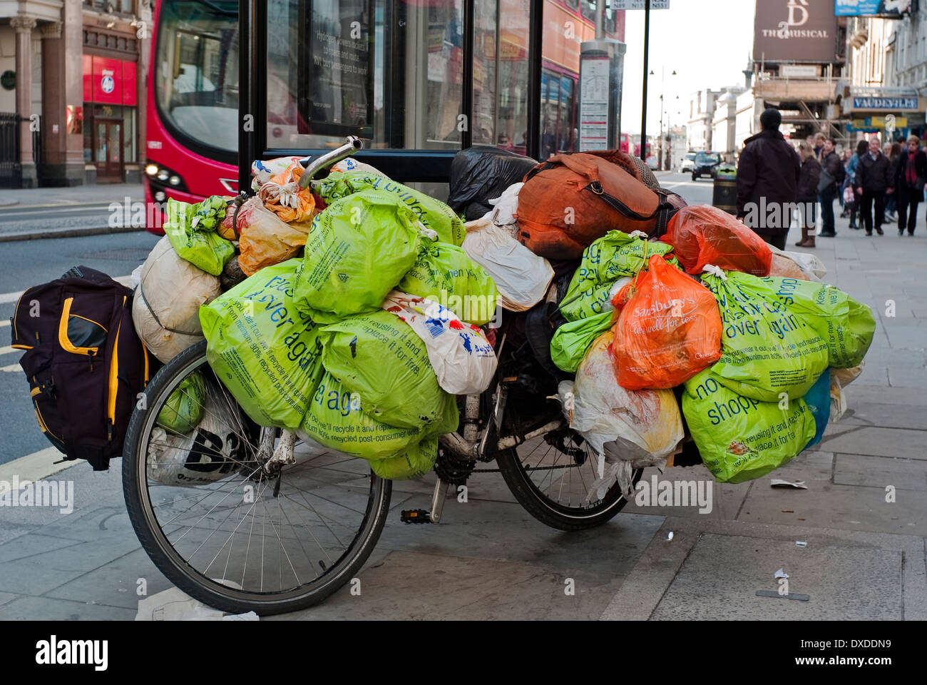 Le persone senza fissa dimora beni mondani in sacchetti di plastica appeso di una bicicletta a Londra Fermata Bus Foto Stock