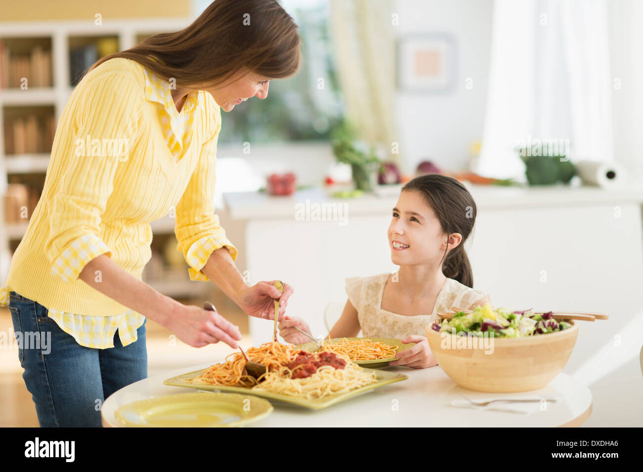 Madre e figlia (8-9) mangiare pasta Foto Stock