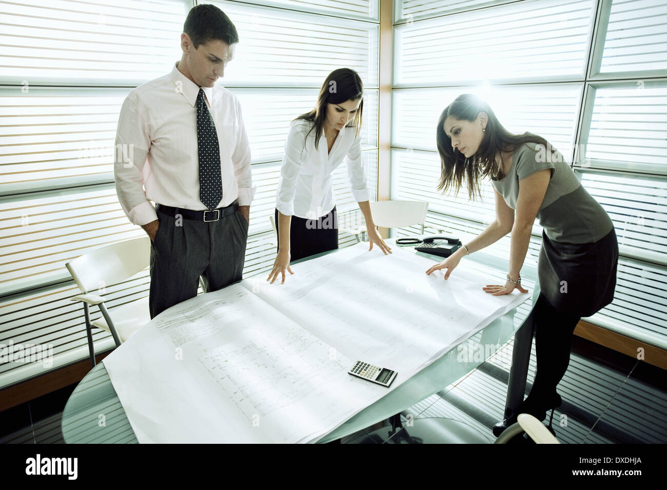 Professionisti alla ricerca di piani architettonici sulla scrivania Foto Stock