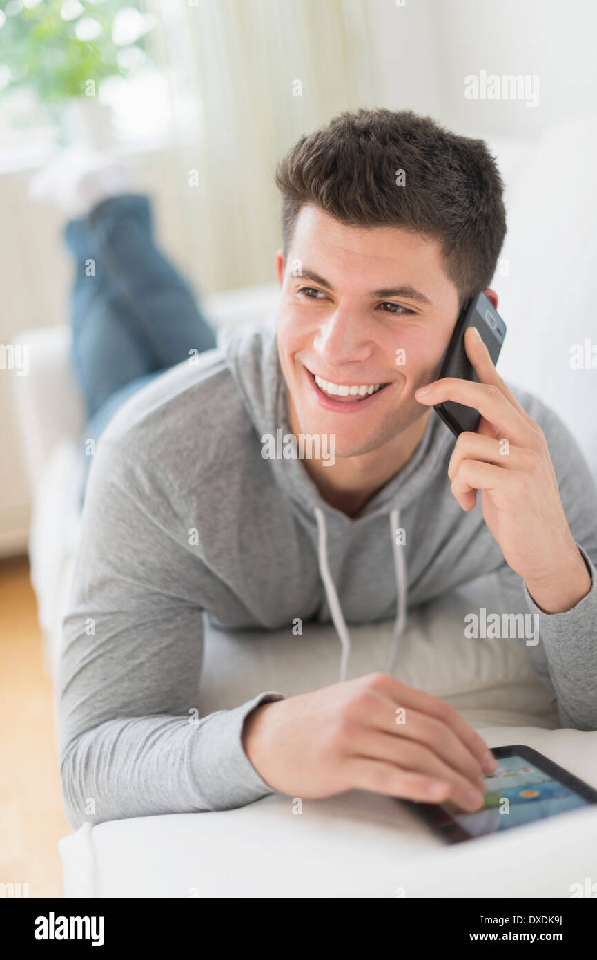 Giovane uomo utilizzando tablet e parla al telefono Foto Stock