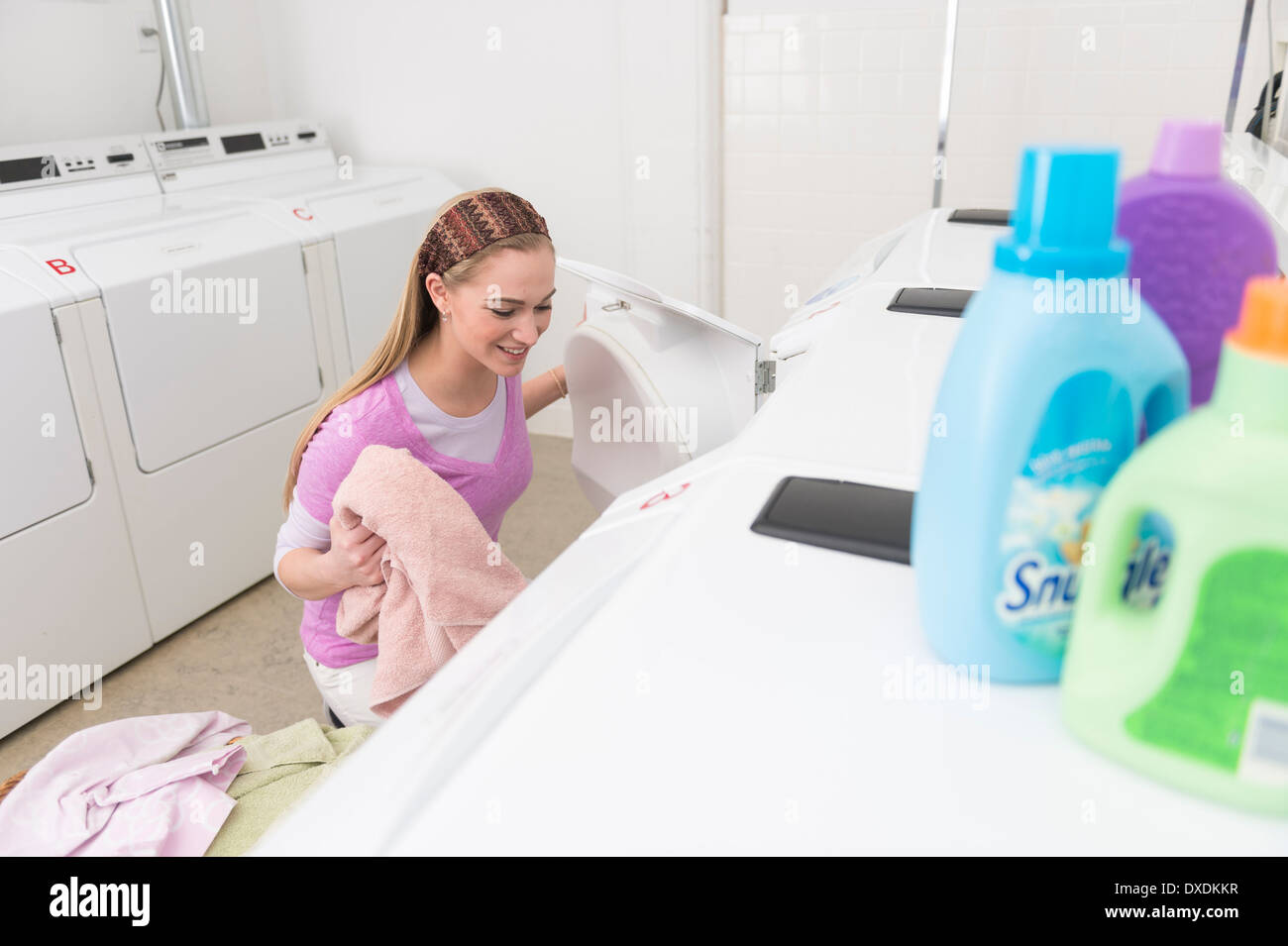 Donna caricamento della biancheria nella macchina di lavaggio Foto Stock