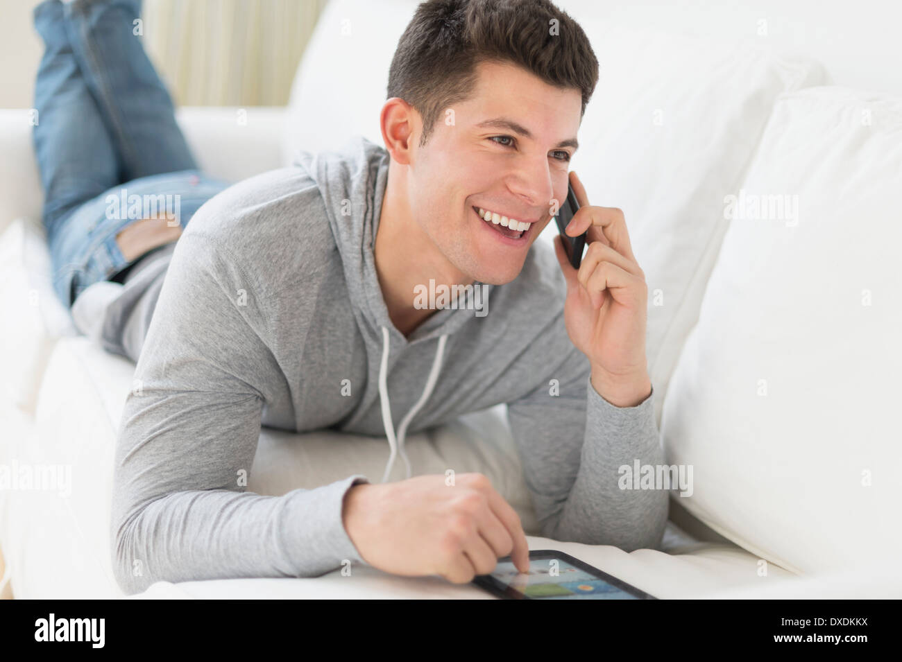 Giovane uomo utilizzando tablet e parla al telefono Foto Stock