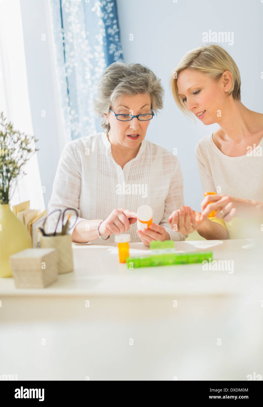 Infermiera e donna matura la lettura di etichette sul flacone di farmaco Foto Stock