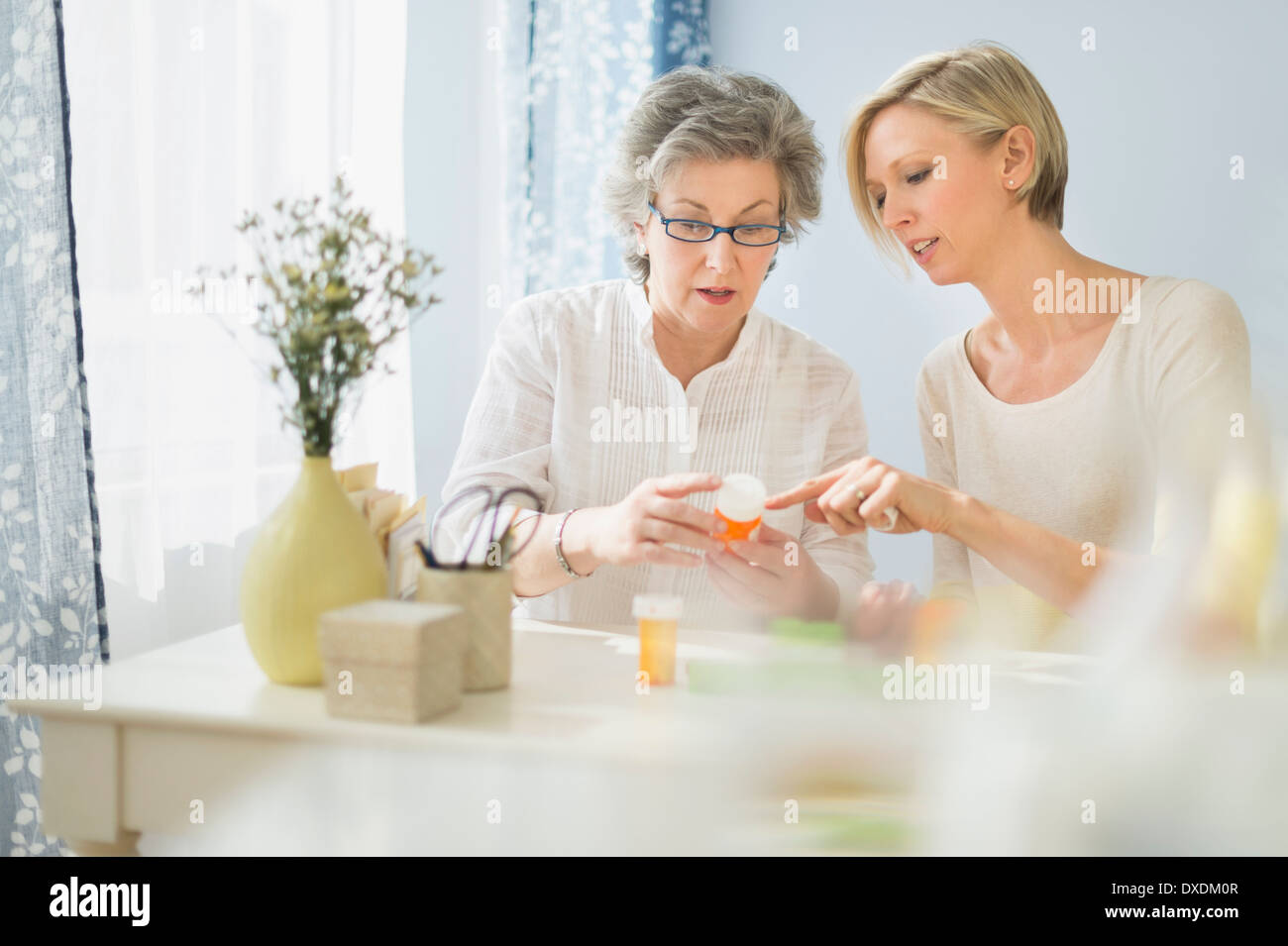 Infermiera e donna matura la lettura di etichette sul flacone di farmaco Foto Stock