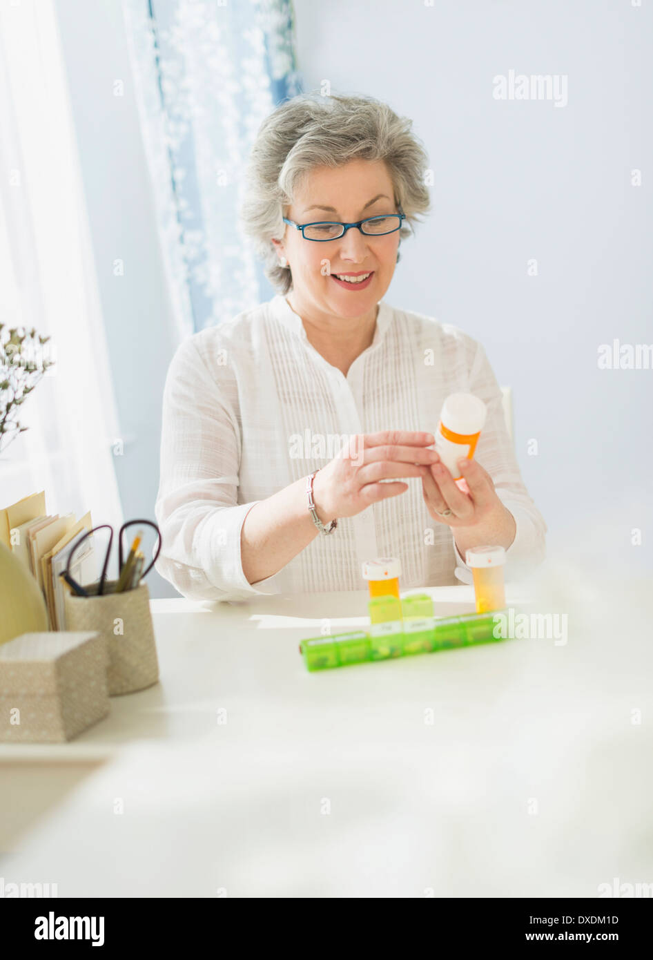 Donna matura la lettura di etichette sul flacone di farmaco Foto Stock