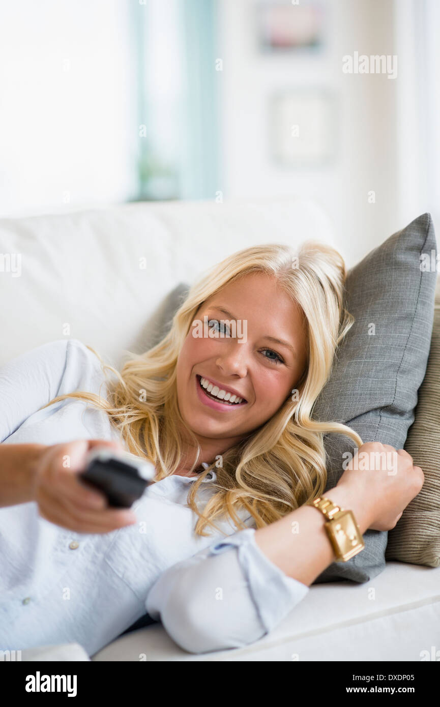 Giovane donna guardando la TV sul divano Foto Stock