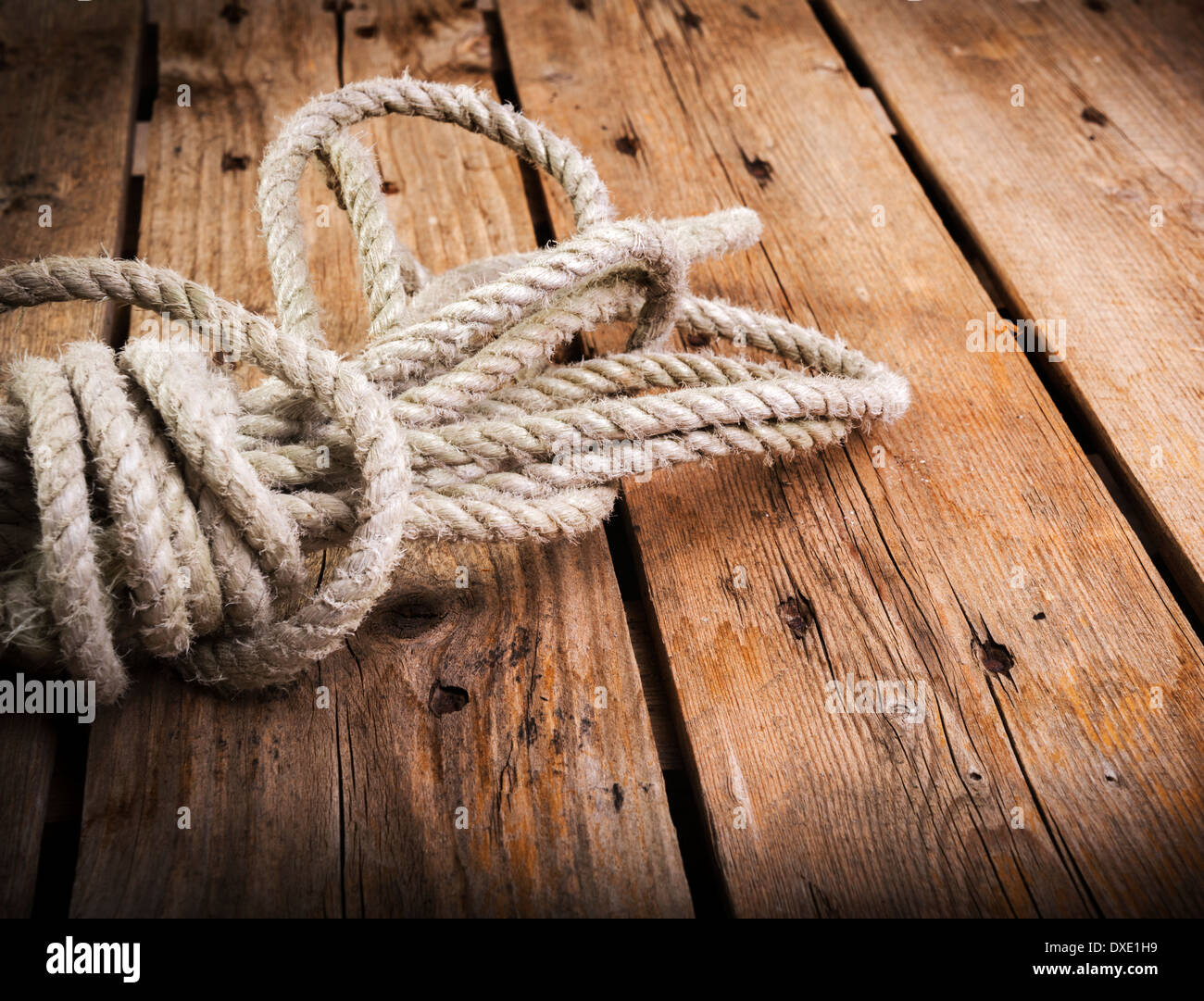 Vecchia corda attorcigliata e legate in un fascio su una ruvida sfondo di legno Foto Stock